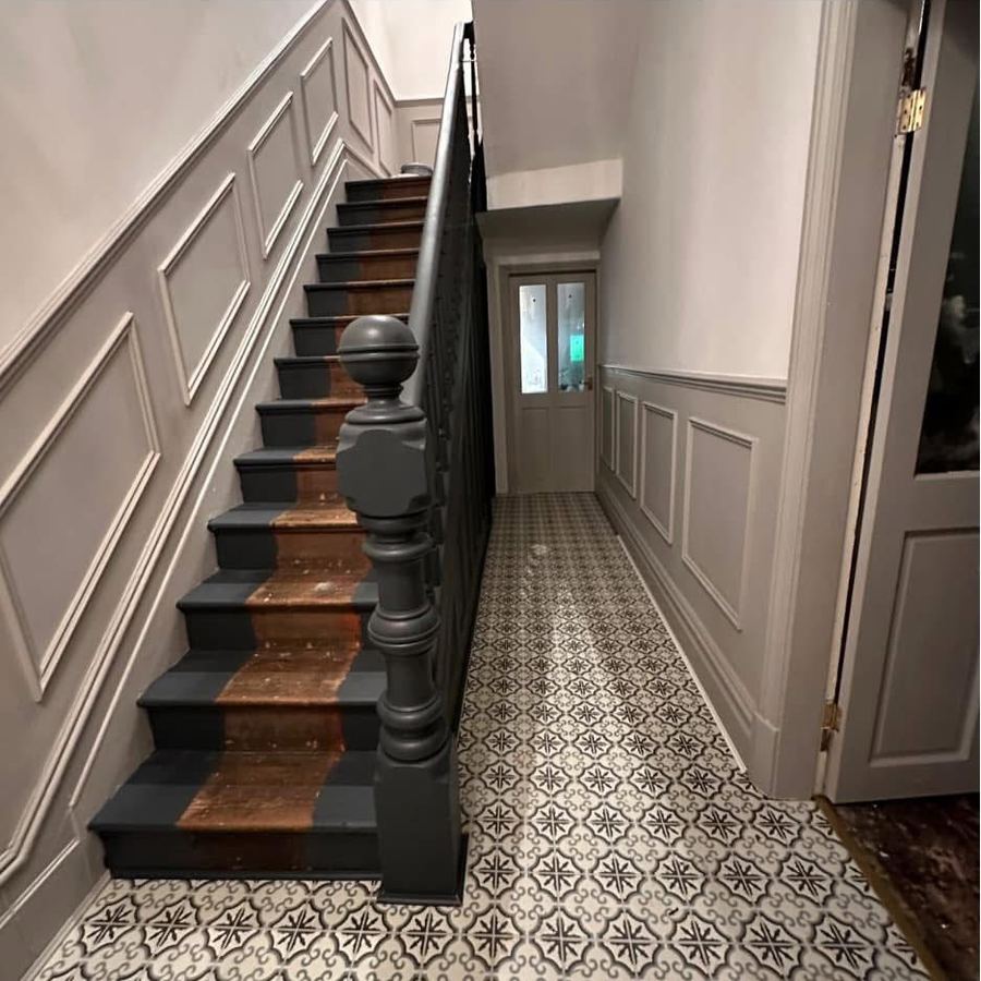 Hallway with panelling, grey woodwork and patterned tiled floor
