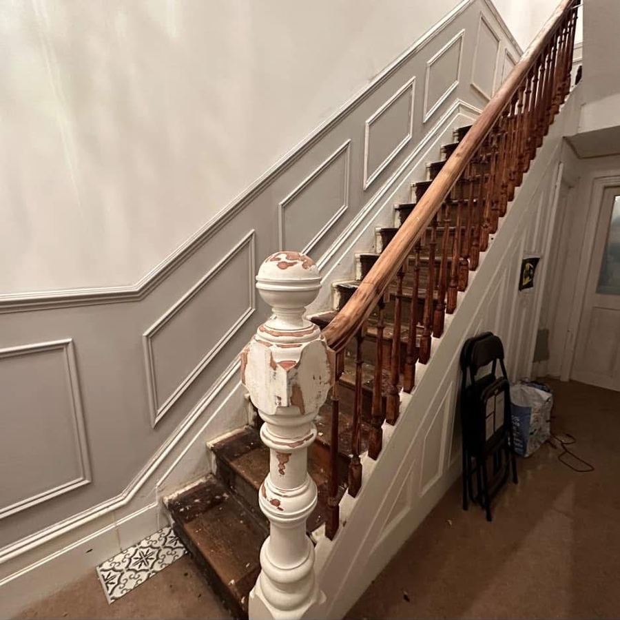 Worn staircase with stripped banister before restoration